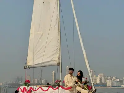 A couple seated on the bow with the Playboy nameplate and Mumbai skyline behind