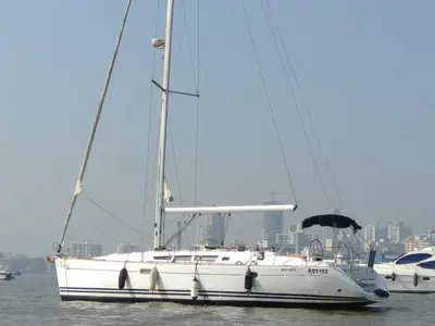 Nava's side profile at anchor with the Mumbai skyline behind