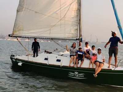 Tikla Queen under sail with a family aboard and the Mumbai skyline behind