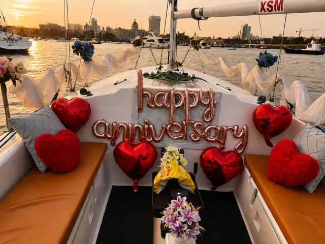 A 'Happy Anniversary' balloon display on deck with the Gateway of India and Taj Mahal Palace visible at golden hour